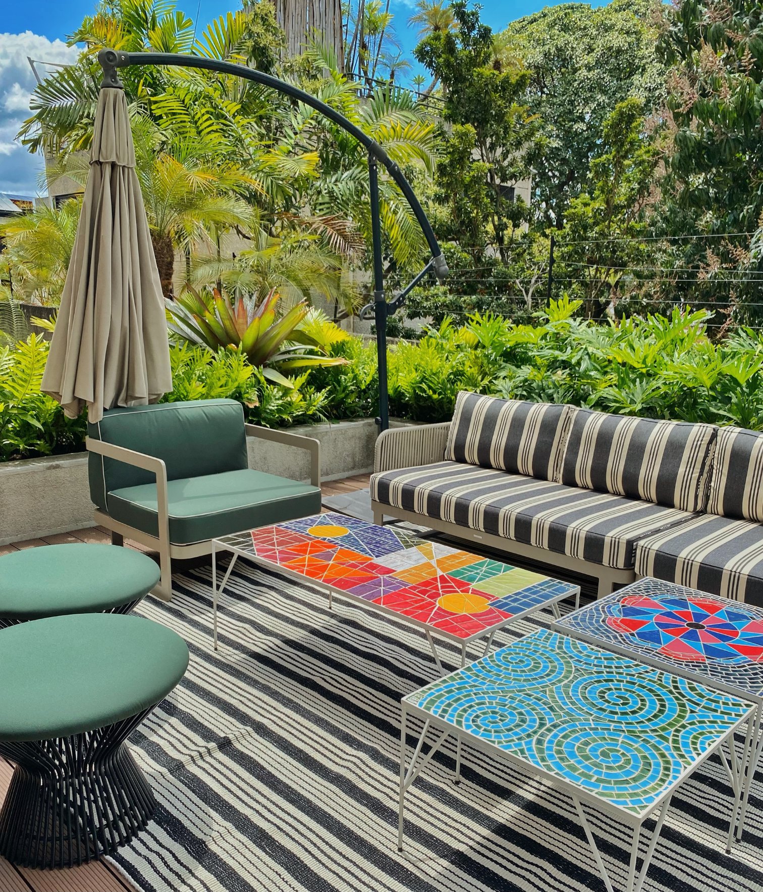 Muebles en la terraza de tela y alfombra de rayas con mesas con mosaicos.