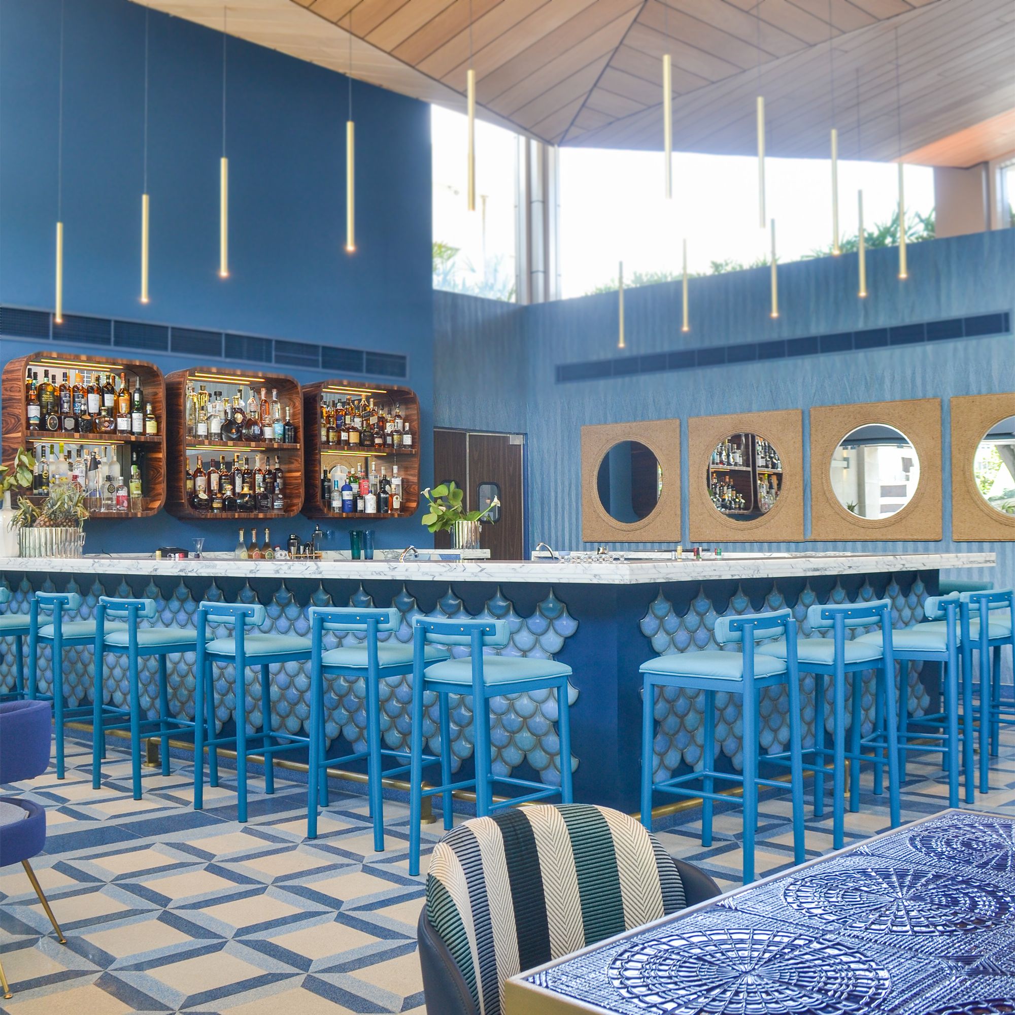 Bar en tonos azules de un restaurante con detalles de escamas texturizadas y sillas altas