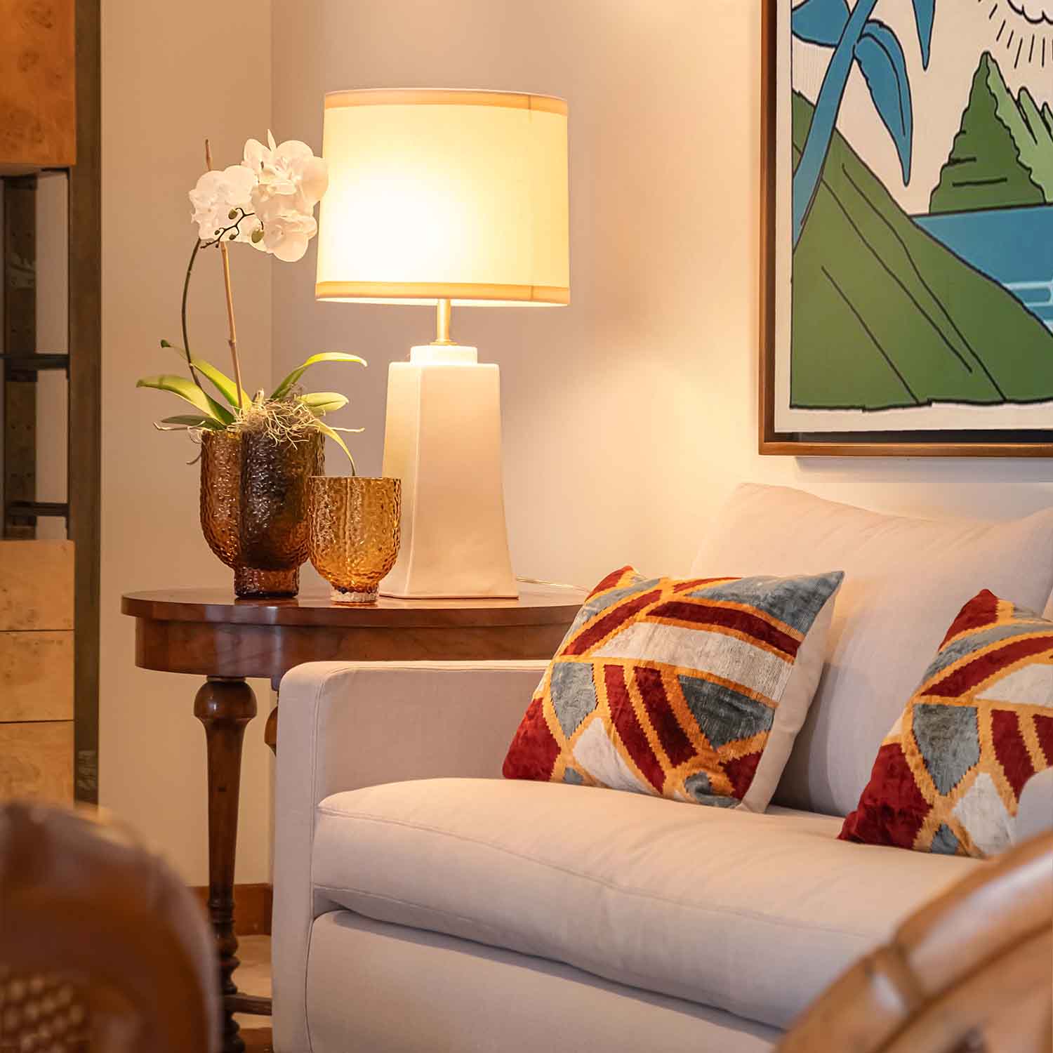 white couch next to a side table with a white lamp