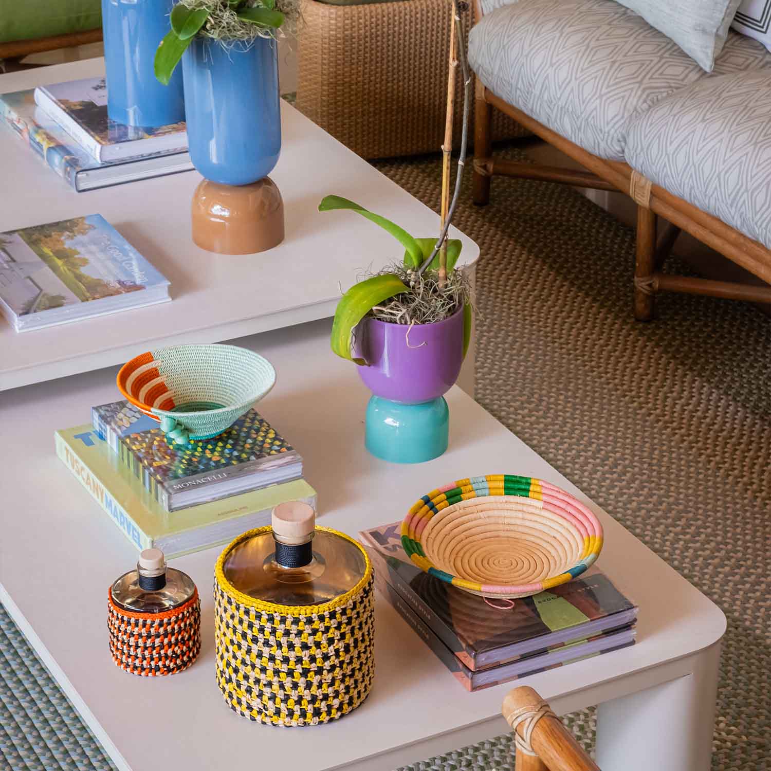 Mesa de café blanca decorada con libros y floreros de varios colores