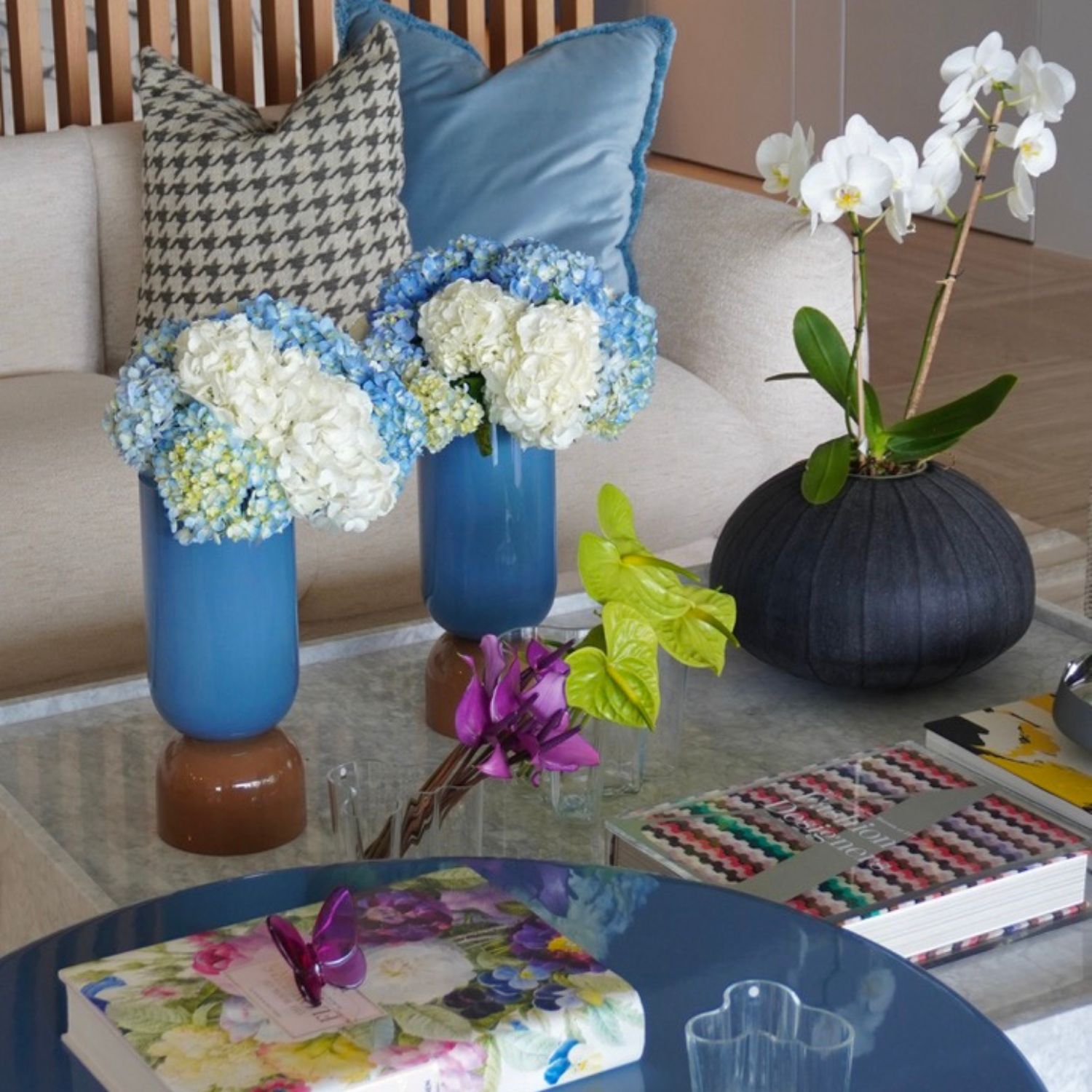 Decoración floral sobre mesa de centro con hortensias azules, orquídeas blancas y detalles en morado y verde, diseño de Volante Studio.