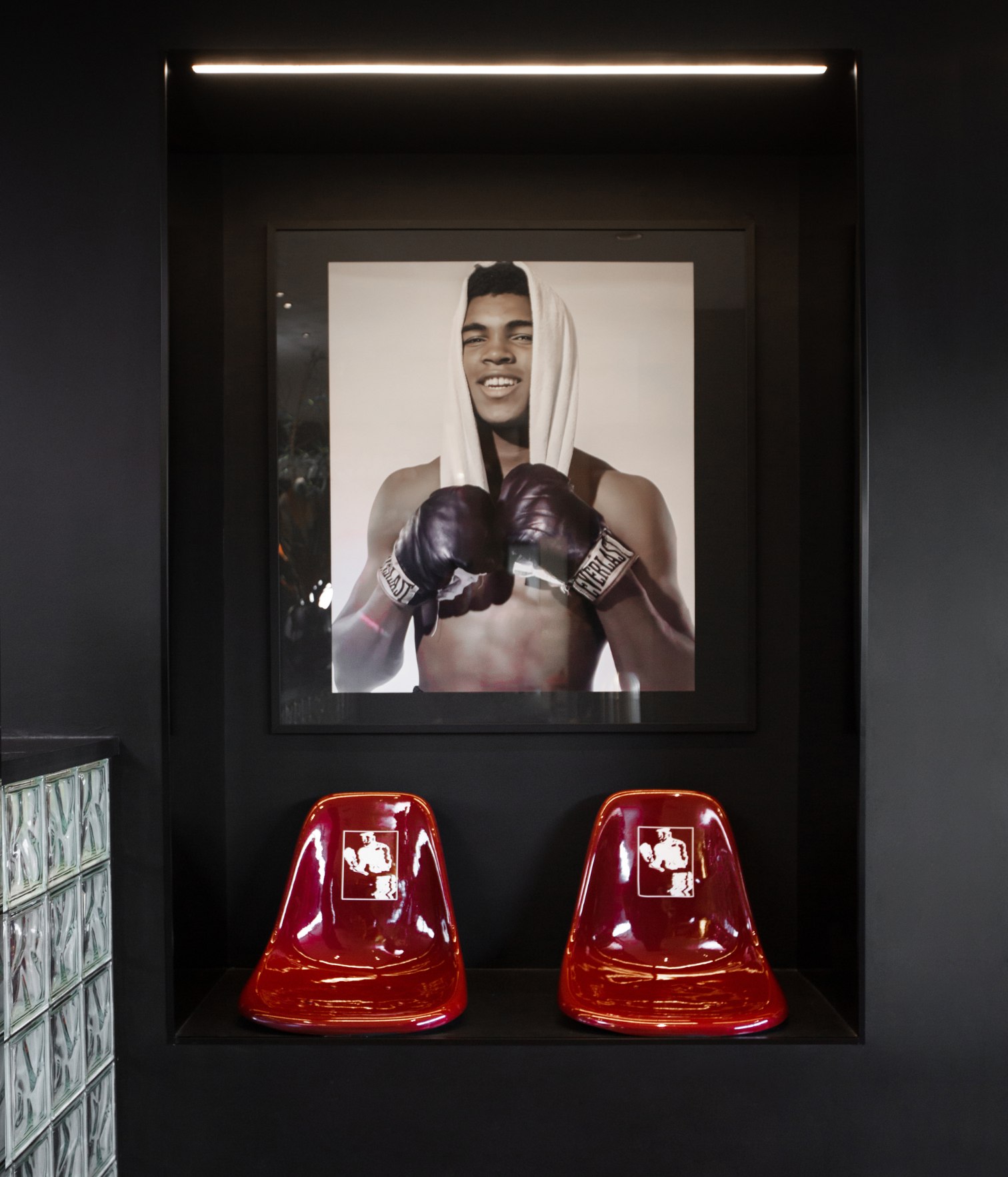 Boxing-inspired lounge area at Swiitch Gym Caracas featuring a Muhammad Ali portrait and iconic red chairs