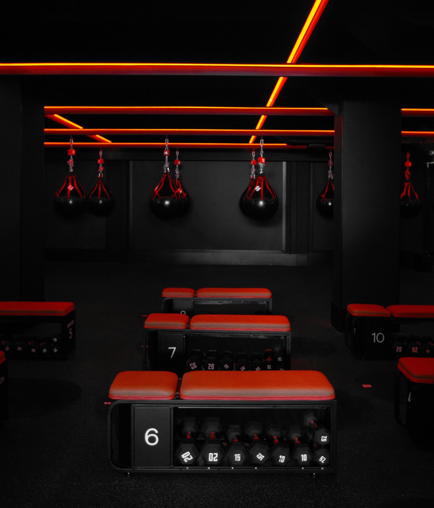 Sala de entrenamiento en Swiitch Gym Caracas con sacos de boxeo, iluminación roja y estaciones numeradas