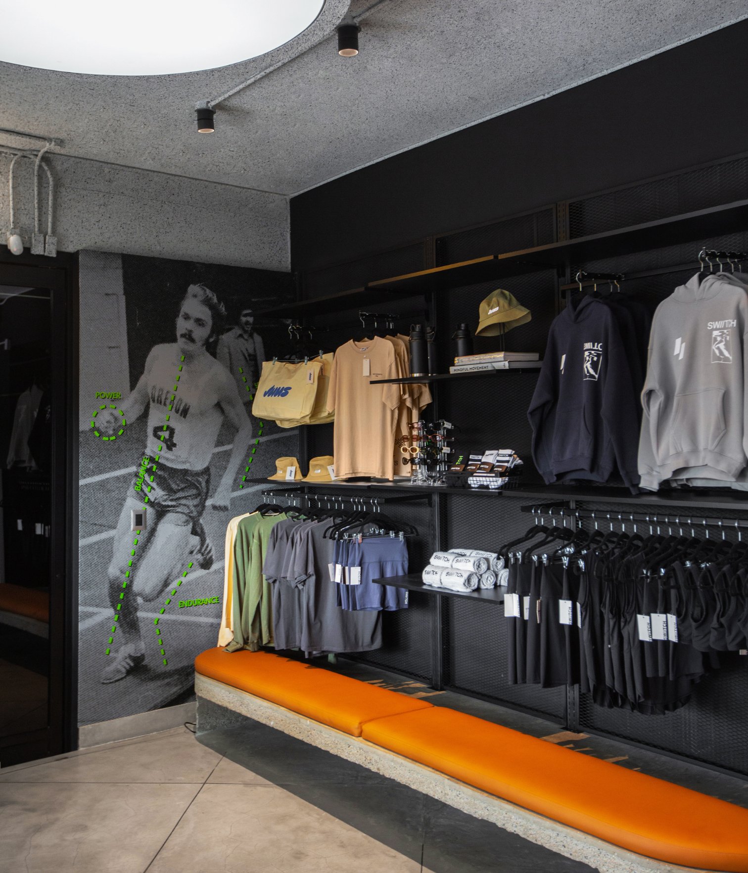 Área de tienda en Swiitch Gym Caracas con ropa deportiva, accesorios y mobiliario industrial en tonos oscuros