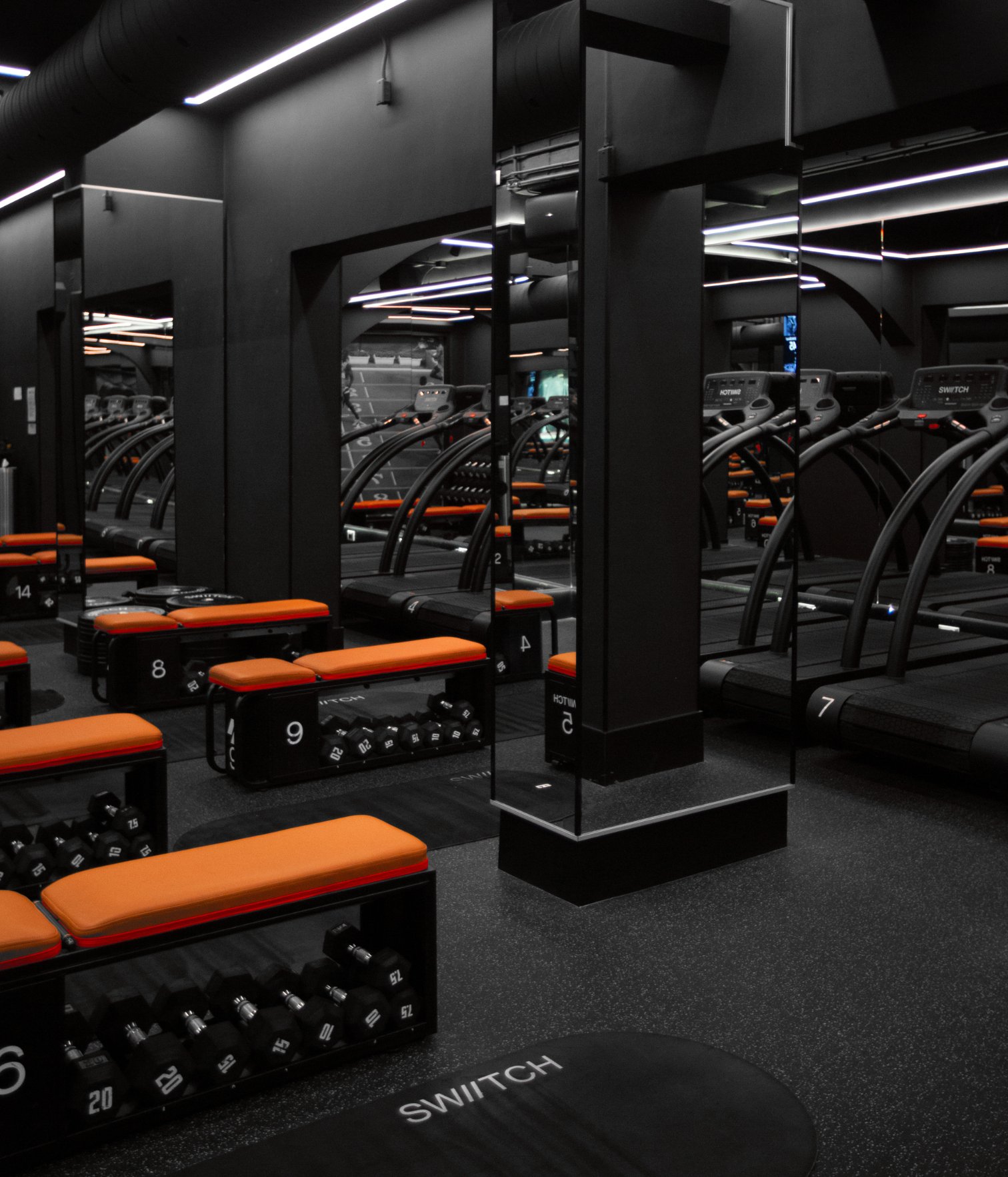 Training room at Swiitch Gym Caracas with treadmills, strength benches, mirrors, and a high-contrast modern fitness design