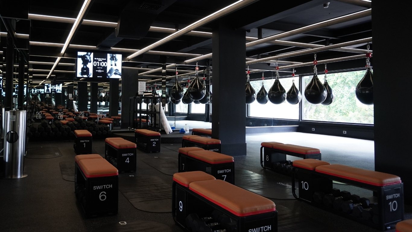Sala de entrenamiento del gimnasio SWIITCH en Altamira, con sacos de boxeo colgantes, bancas numeradas y espejos de pared completa.