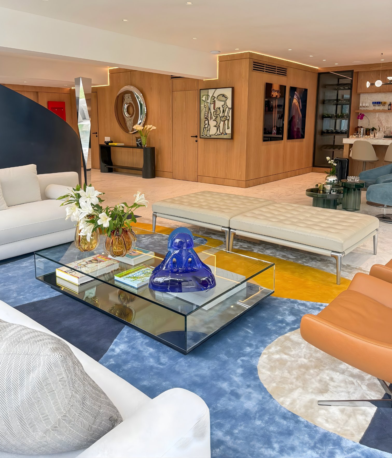 Modern living room with white sofa, glass coffee table, blue sculpture and rug composition in blue and mustard tones