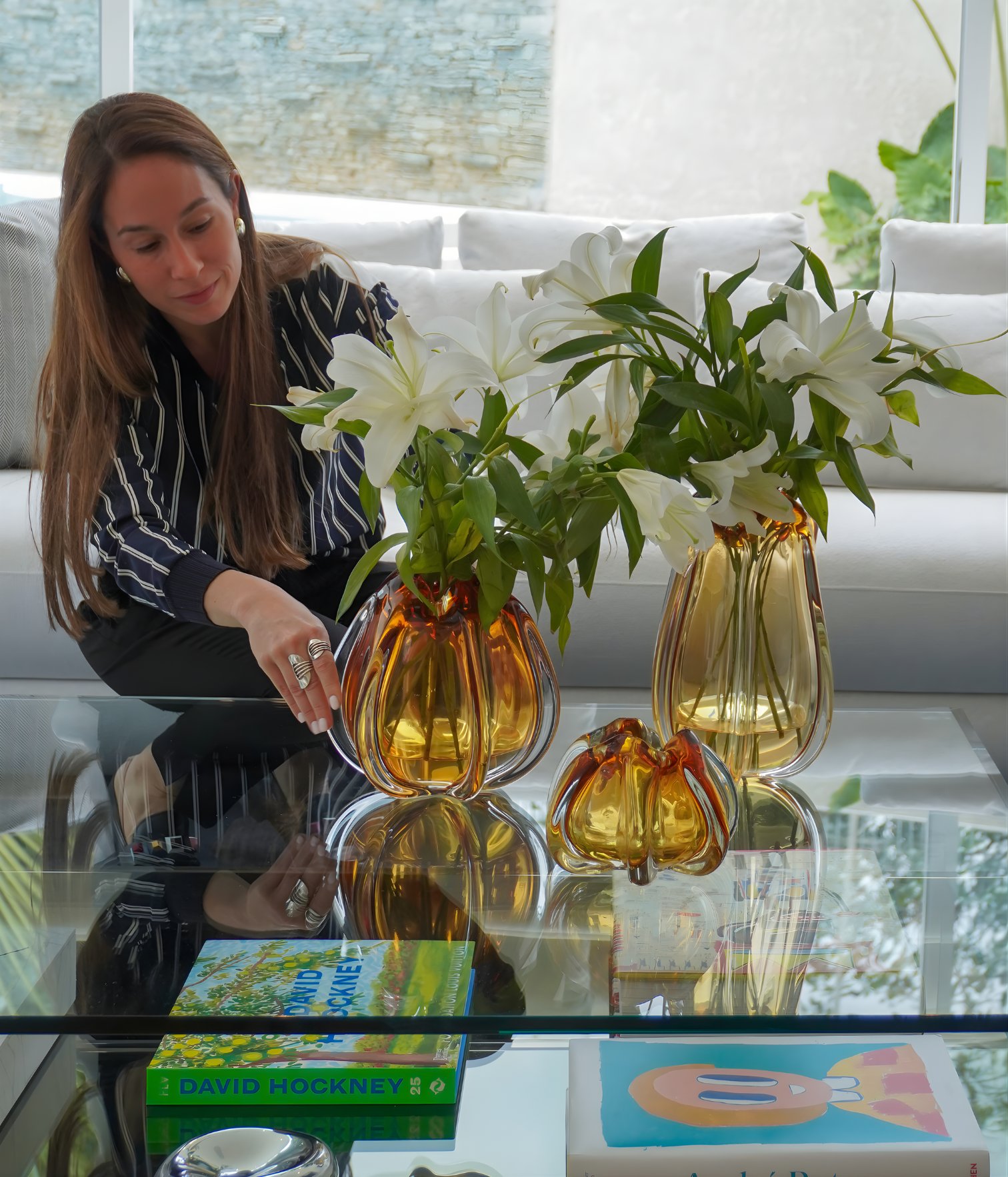 Interior designer Ana Volante styling the coffee table with amber glass vases and white lilies