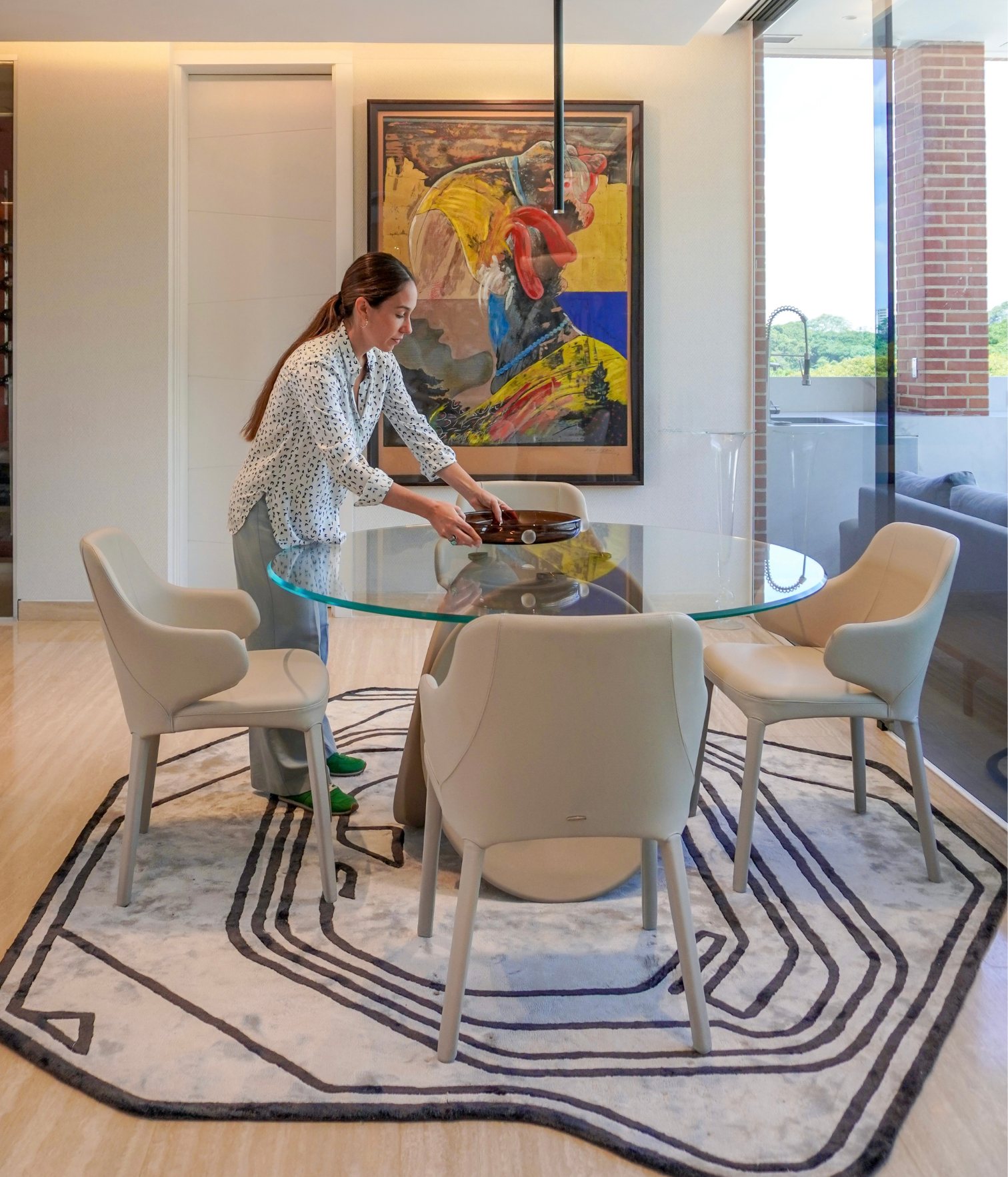 Interior designer Ana Volante styling the dining area with round glass table and upholstered chairs