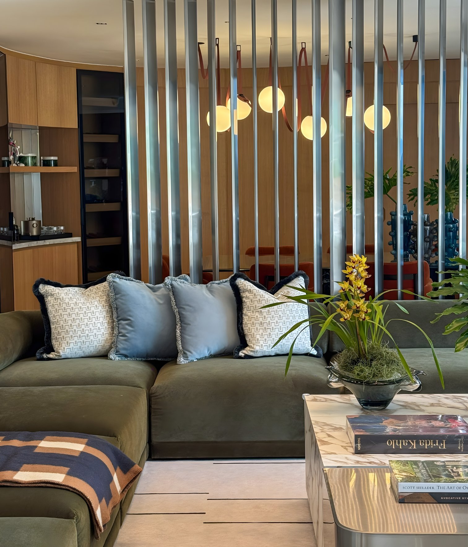 Modern living room with green velvet sofa, decorative cushions and sculptural lighting designed by Ana Volante.