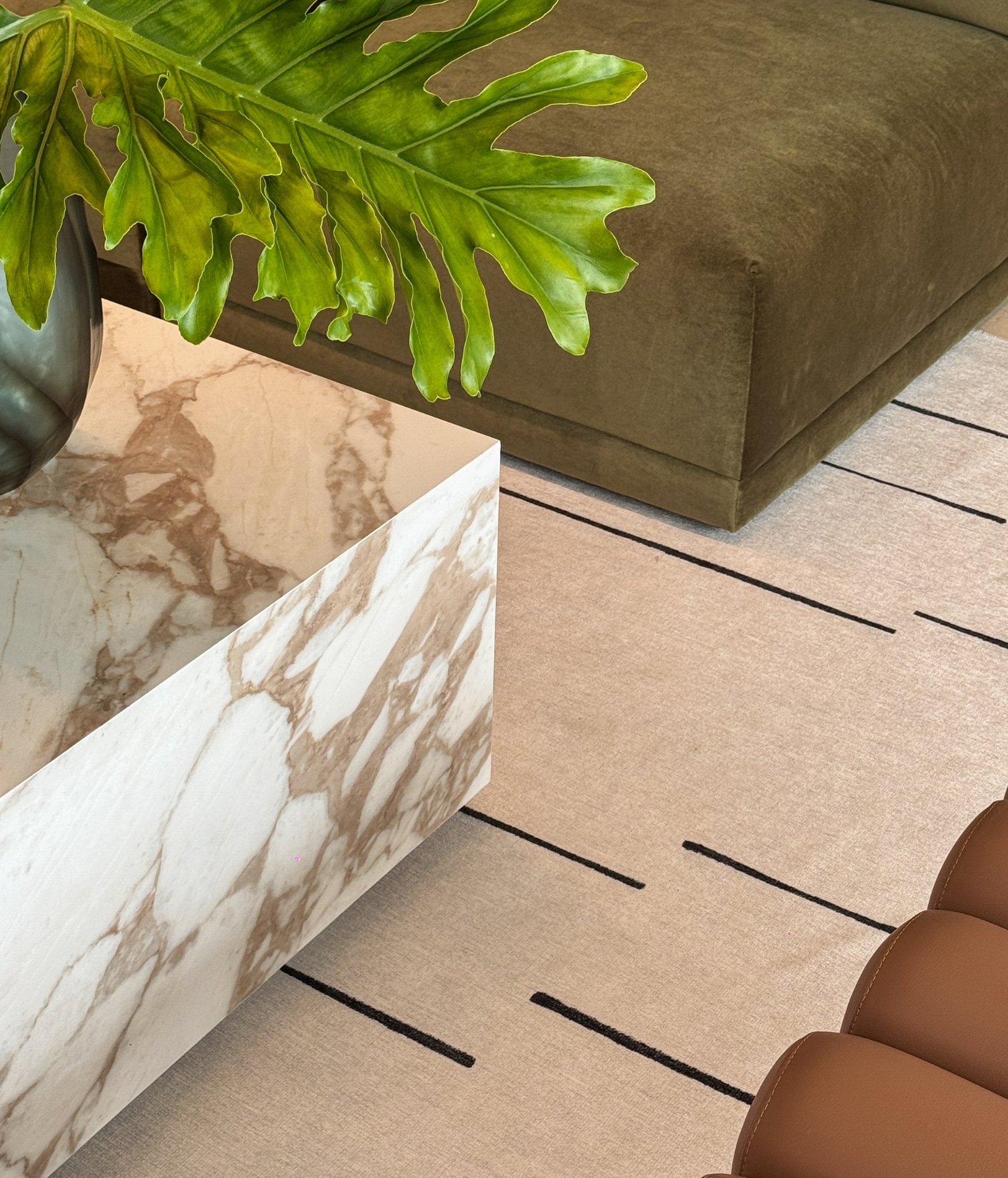Detail of marble coffee table with decorative objects and greenery in an elegant residential living room.