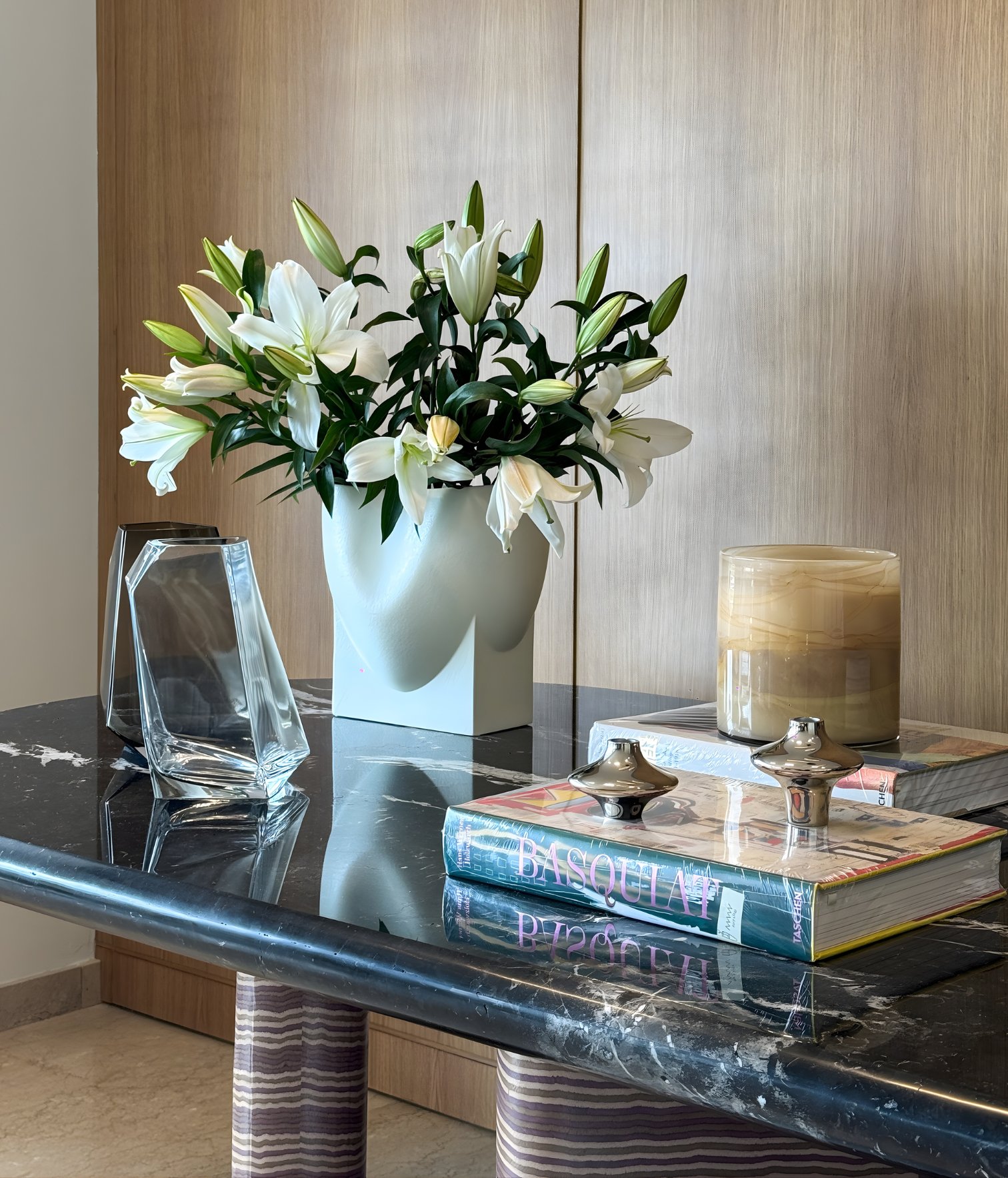 Decorative marble console table styled with flowers, books and glass objects in a residential interior designed by Ana Volante.