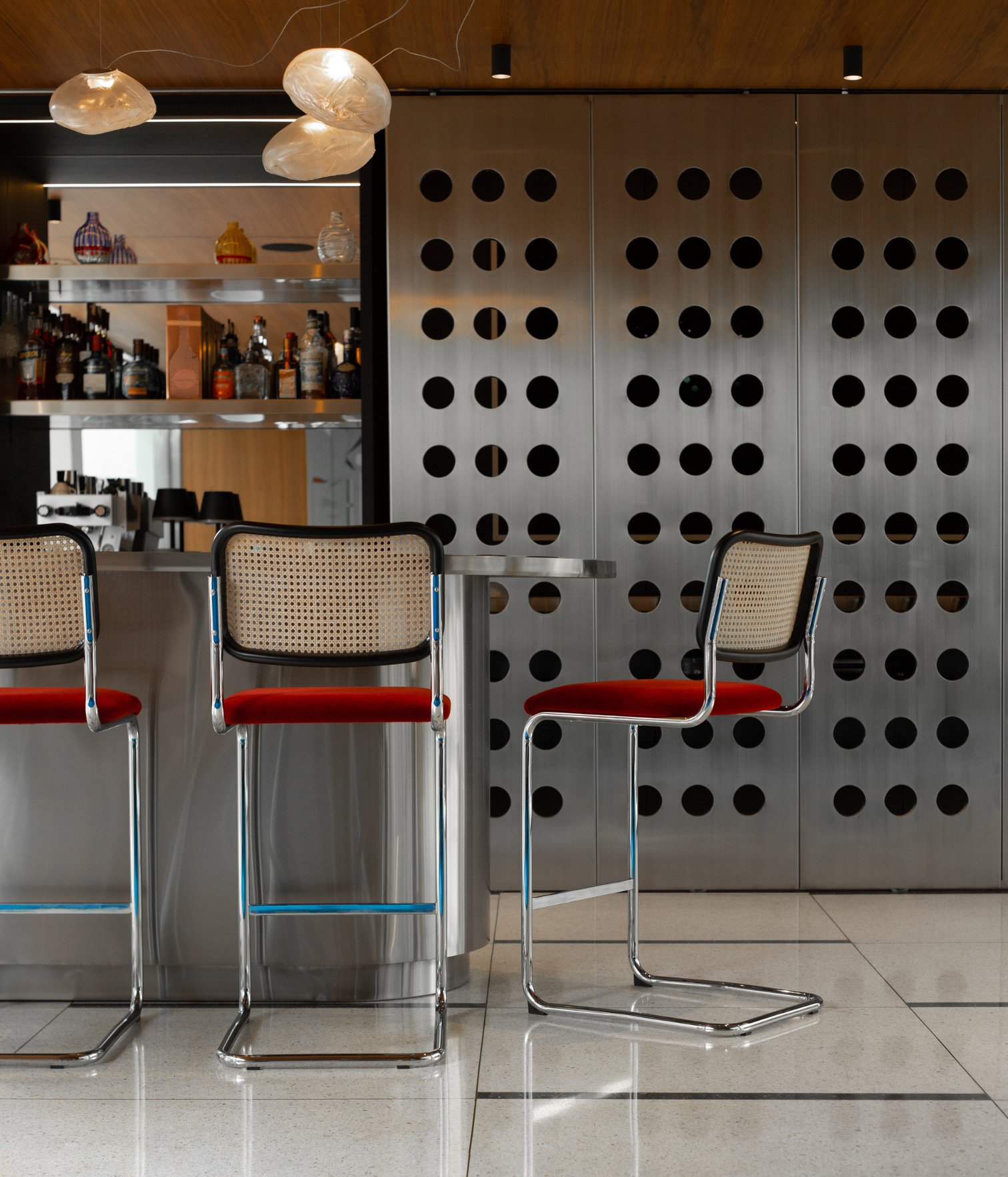 Barra con taburetes, panel metálico perforado y botellero integrado