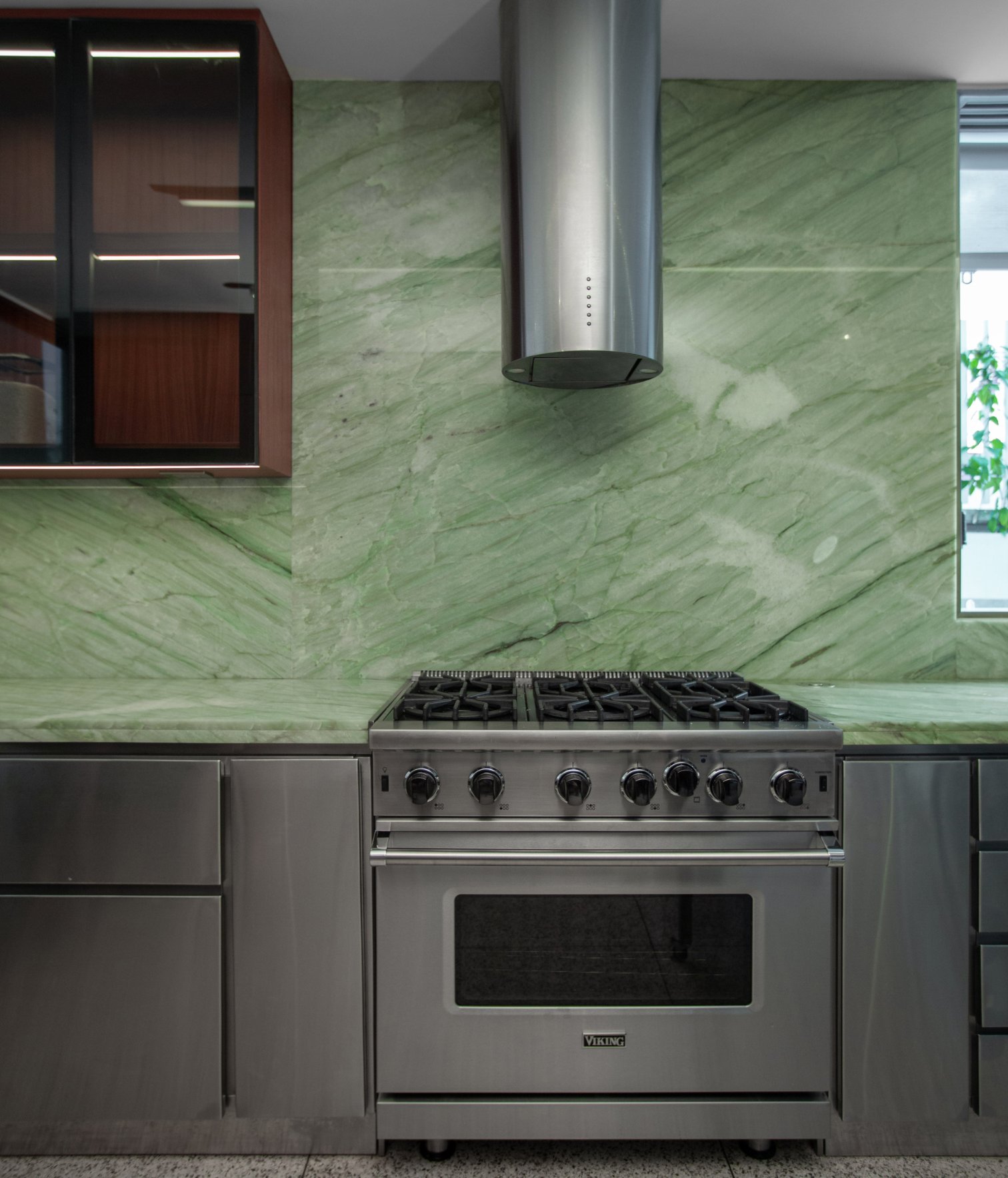 Cocina moderna con salpicadero de piedra verde, electrodomésticos de acero inoxidable y diseño minimalista