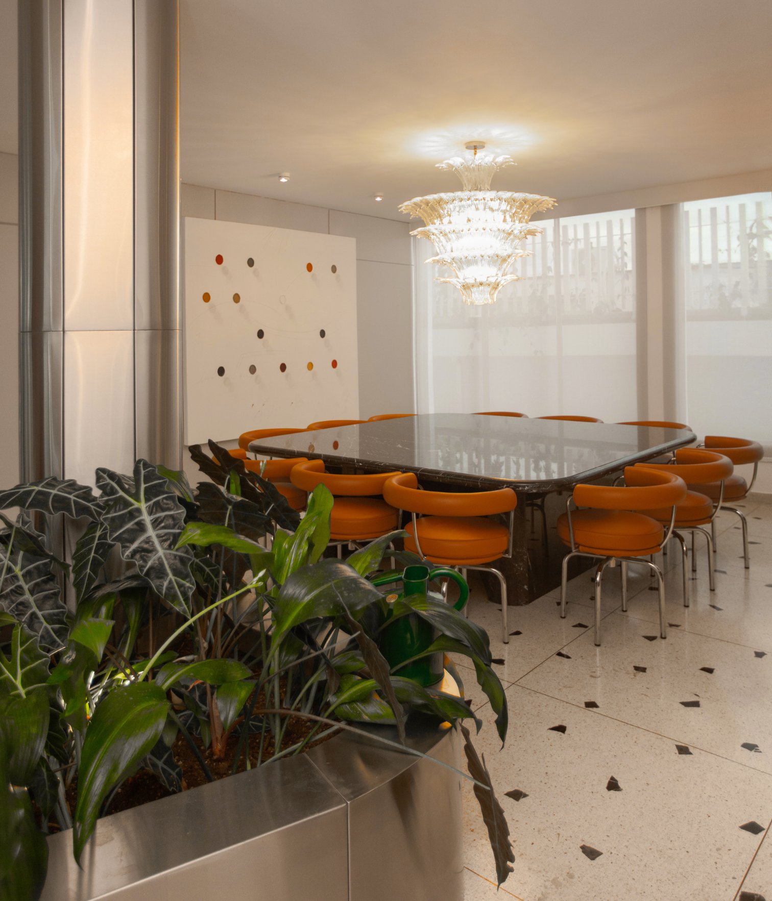 Comedor contemporáneo con mesa de piedra, sillas naranjas y lámpara colgante escultural