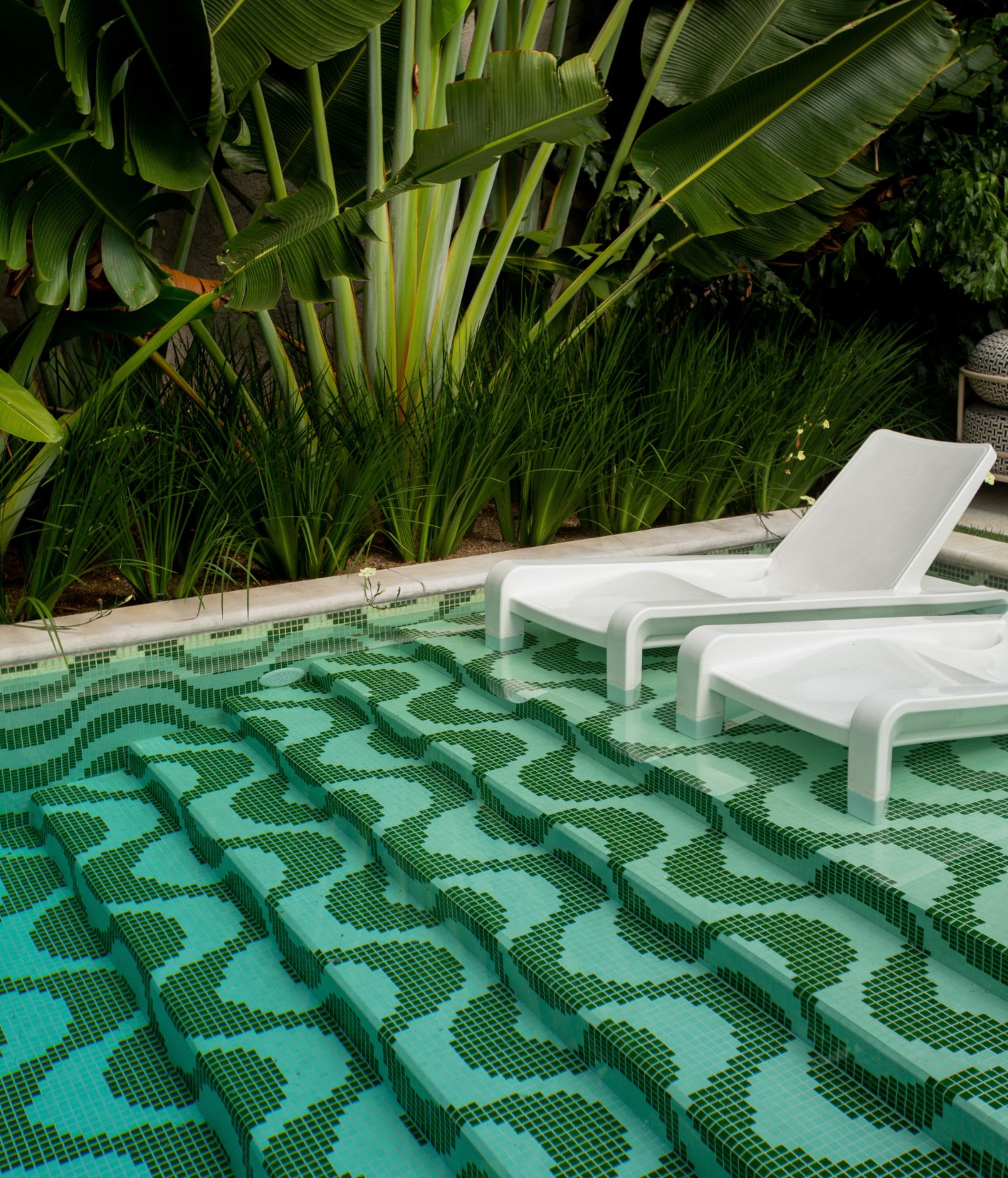 Pool steps with green geometric tiles and built-in lounge chairs