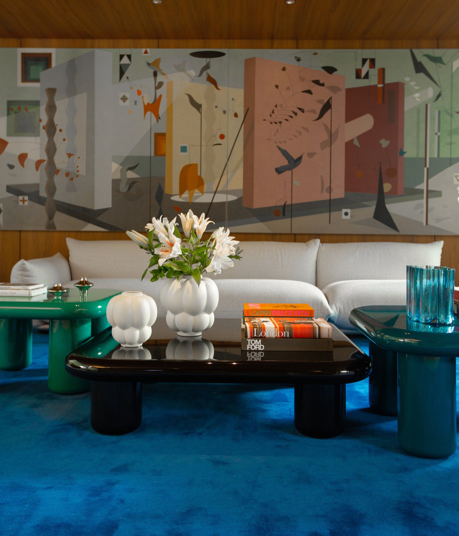 Mesa de centro con libros, jarrones y flores en sala contemporánea